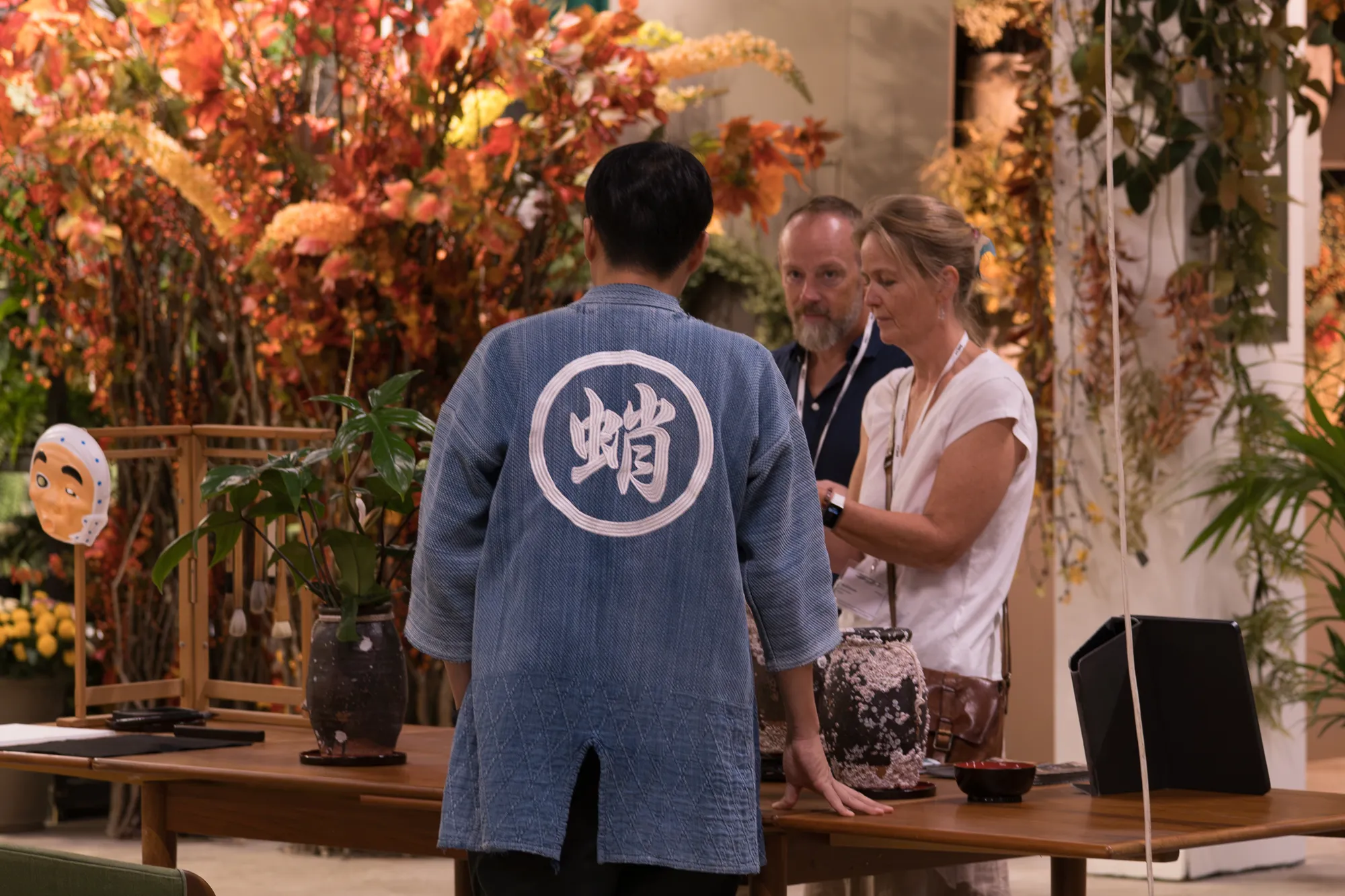 Besøgende ved en stand med japansk keramik og efterårsblomster