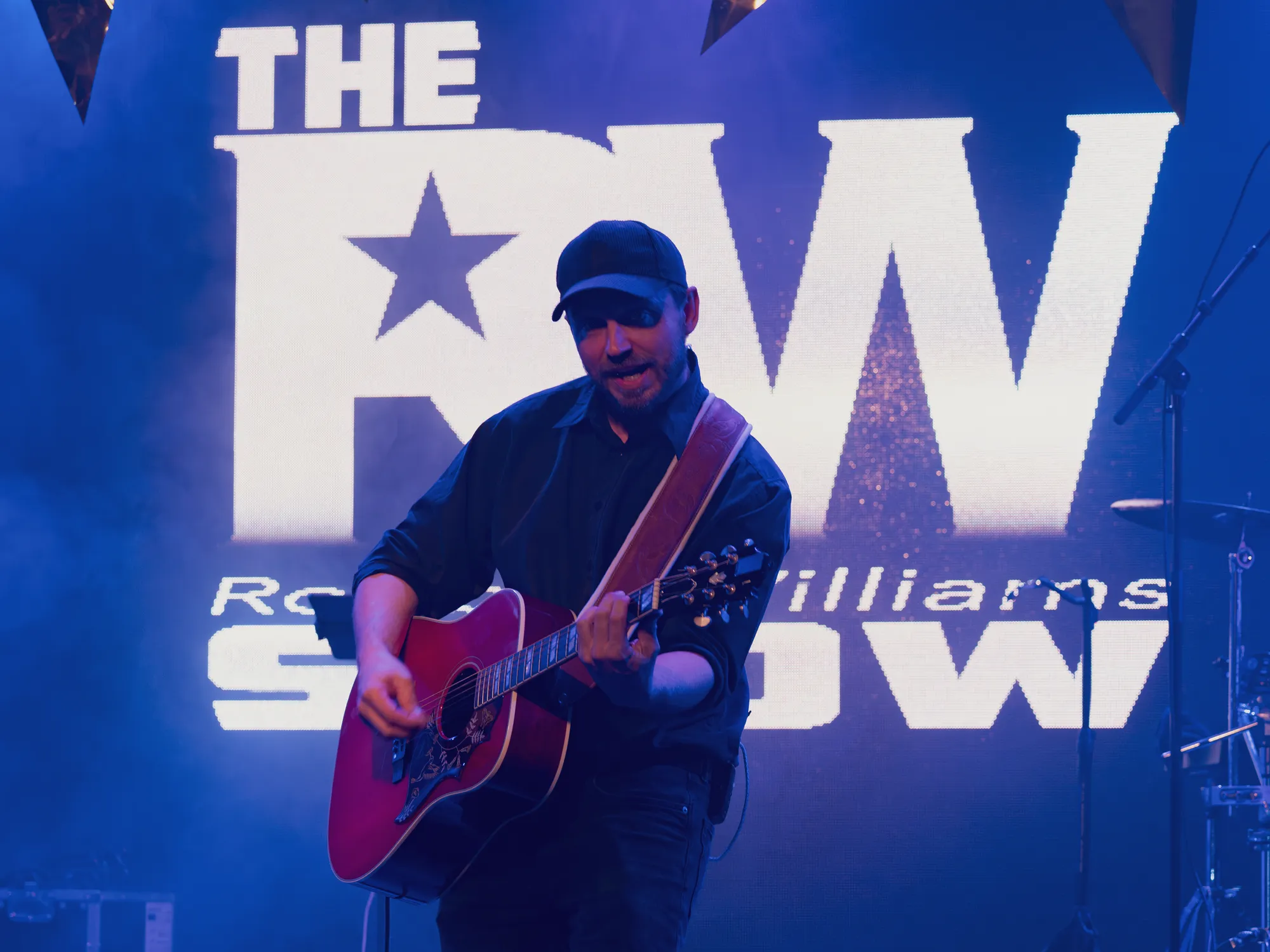 Guitarist på scenen foran The Robbie Williams Show-logoet
